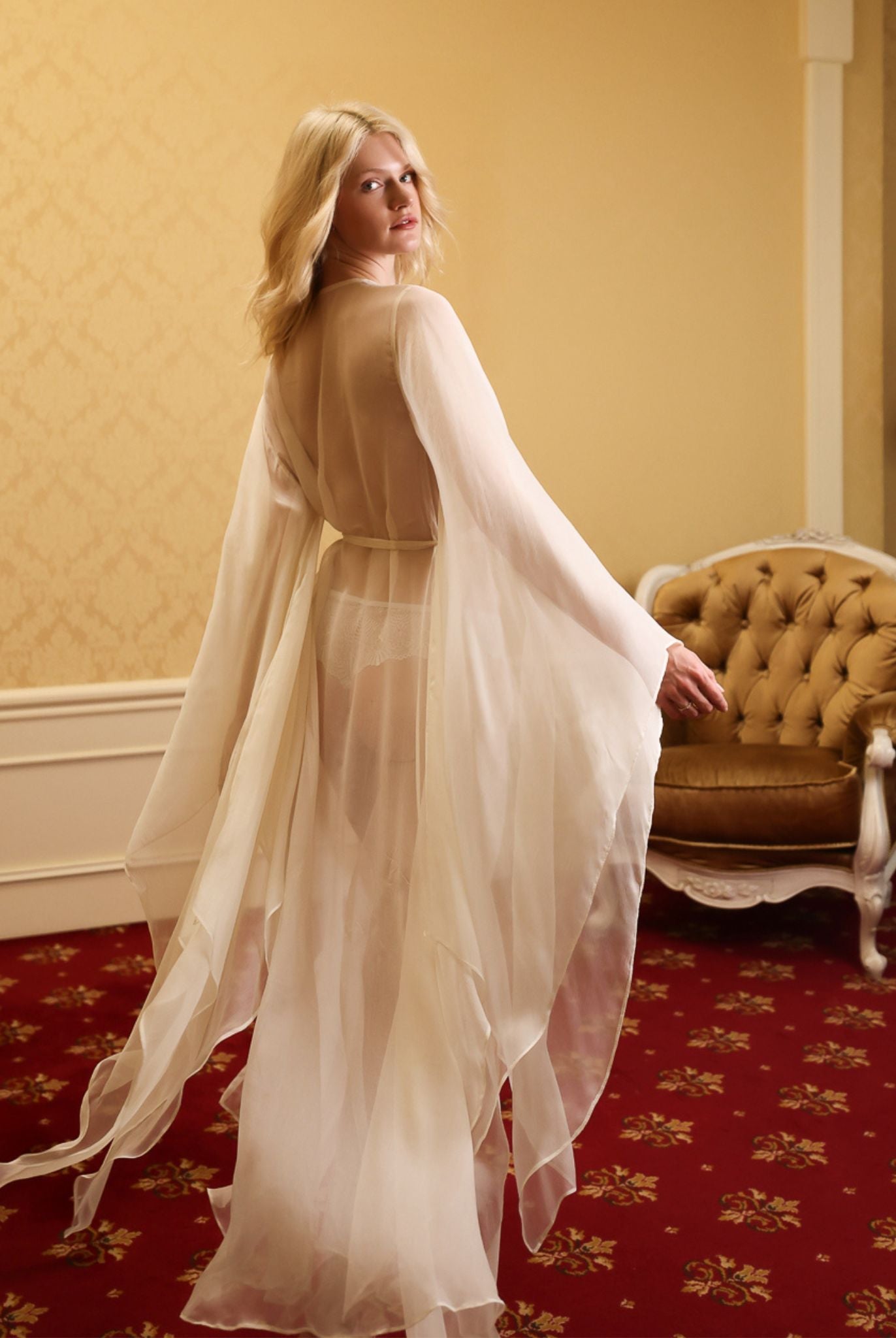 Rear view showing the poetic movement of wide sleeves and sheer hem, creating a beautiful play of light on silk.