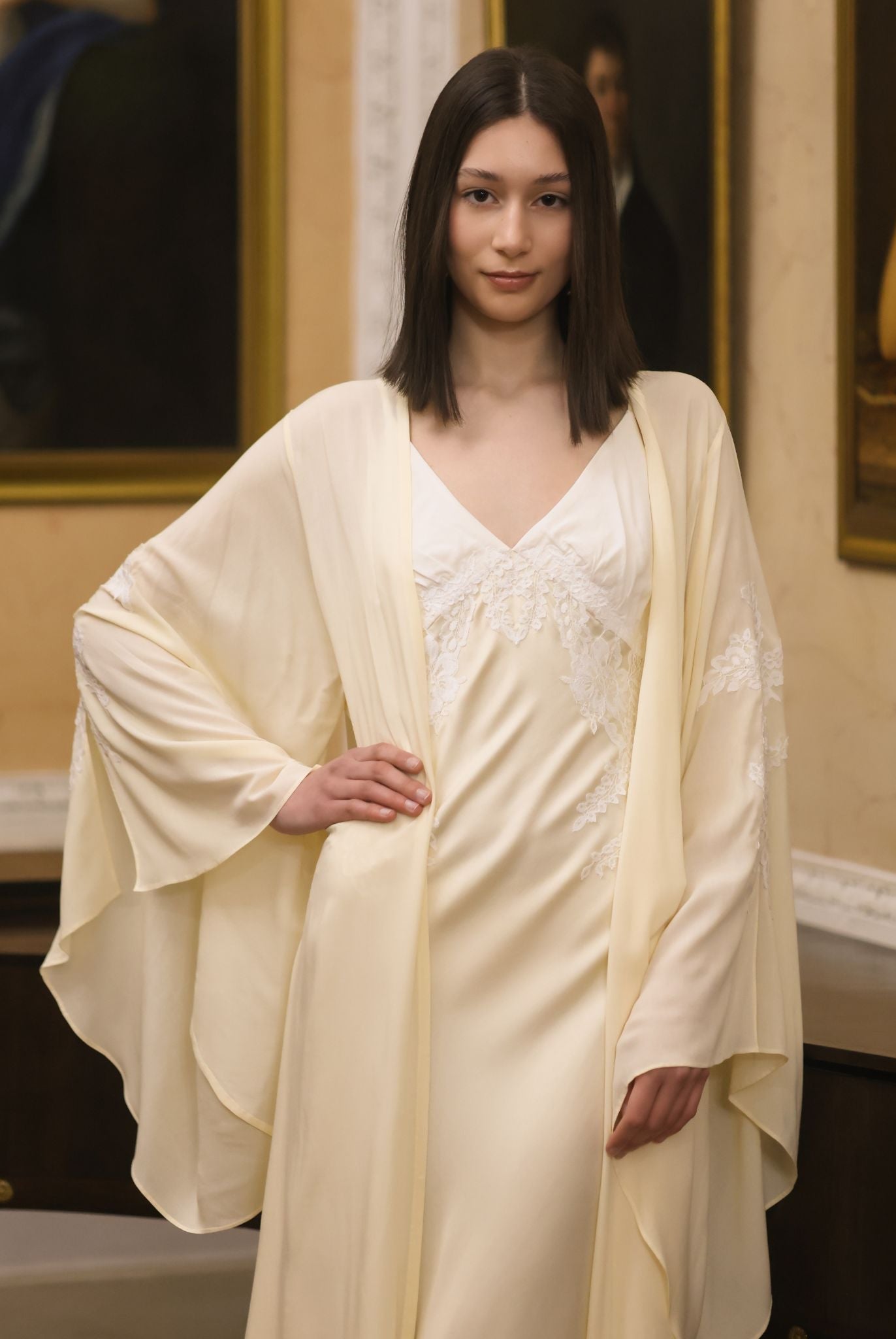 A mid-length shot focusing on the lace appliqué at the bodice and the wide sleeves edged in delicate lace.