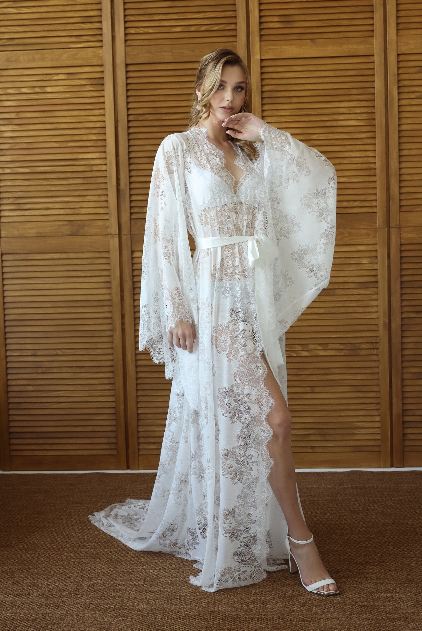 Bride in white lace robe with long train, standing in front of wooden backdrop – KÂfemme