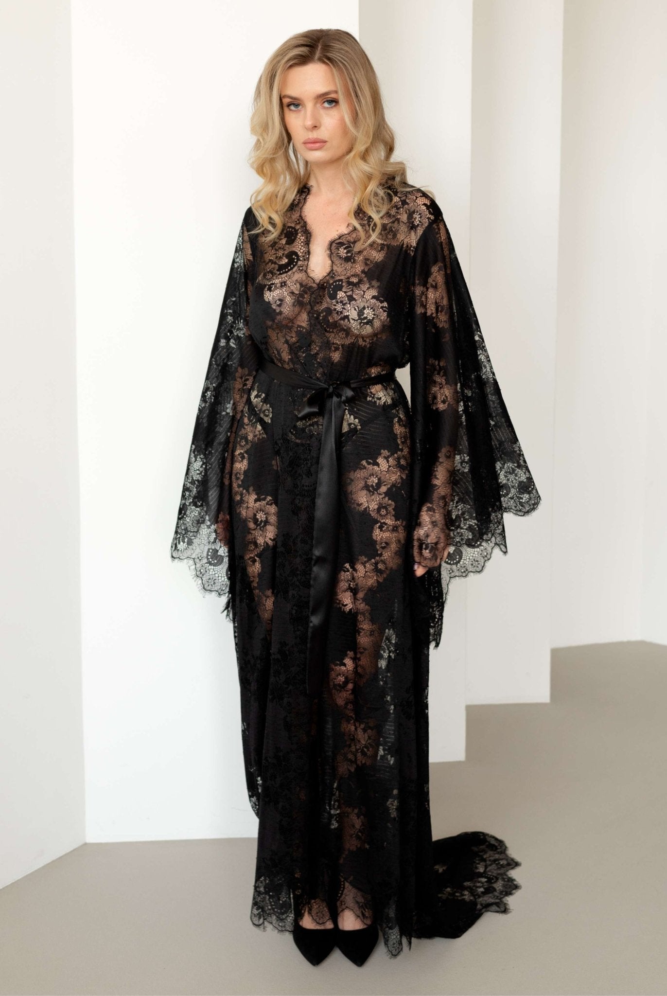 Full-body view of model in sheer black lace robe against white background – KÂfemme
