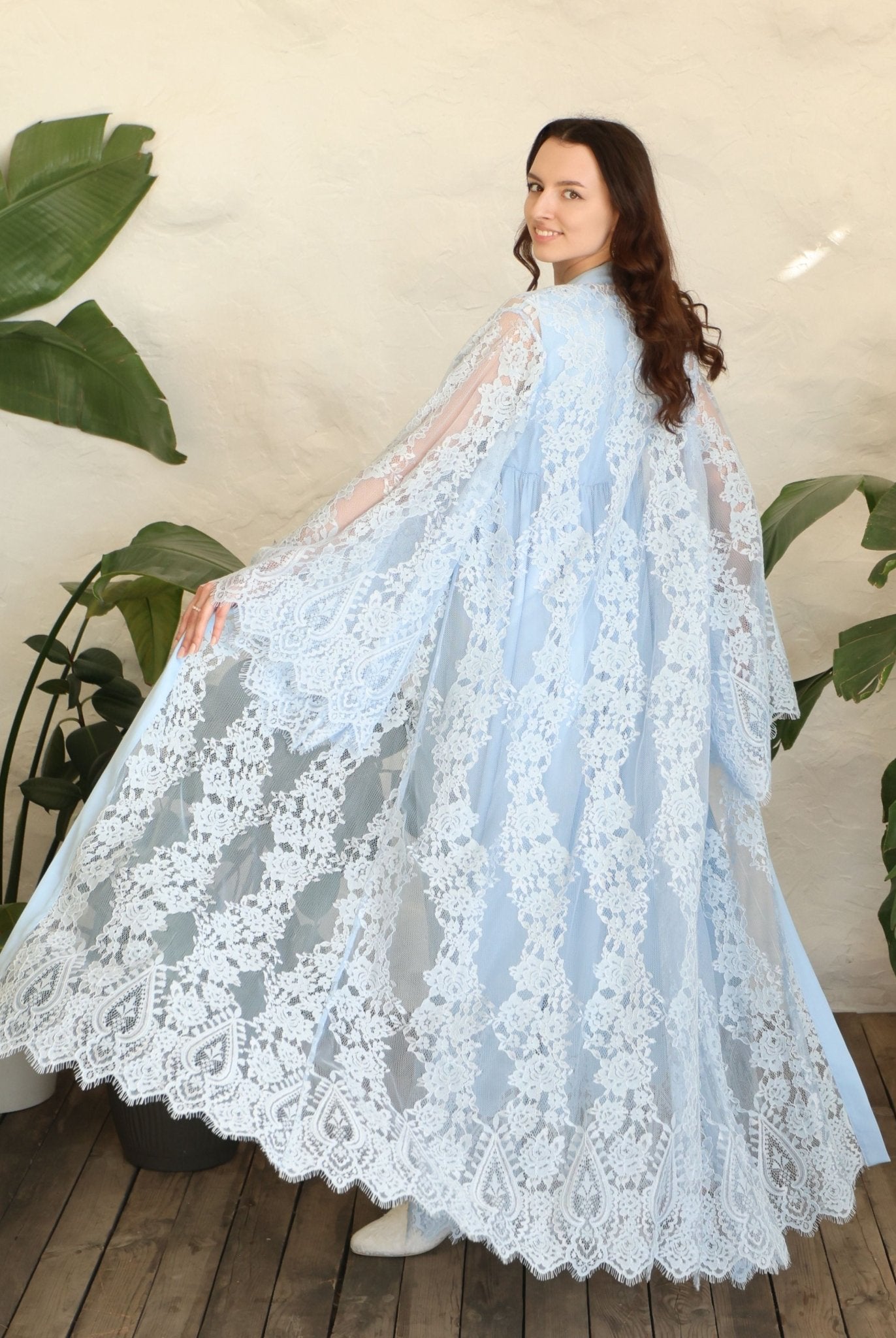 Rear view of the robe in motion, highlighting the voluminous lace and the graceful drape over the body.