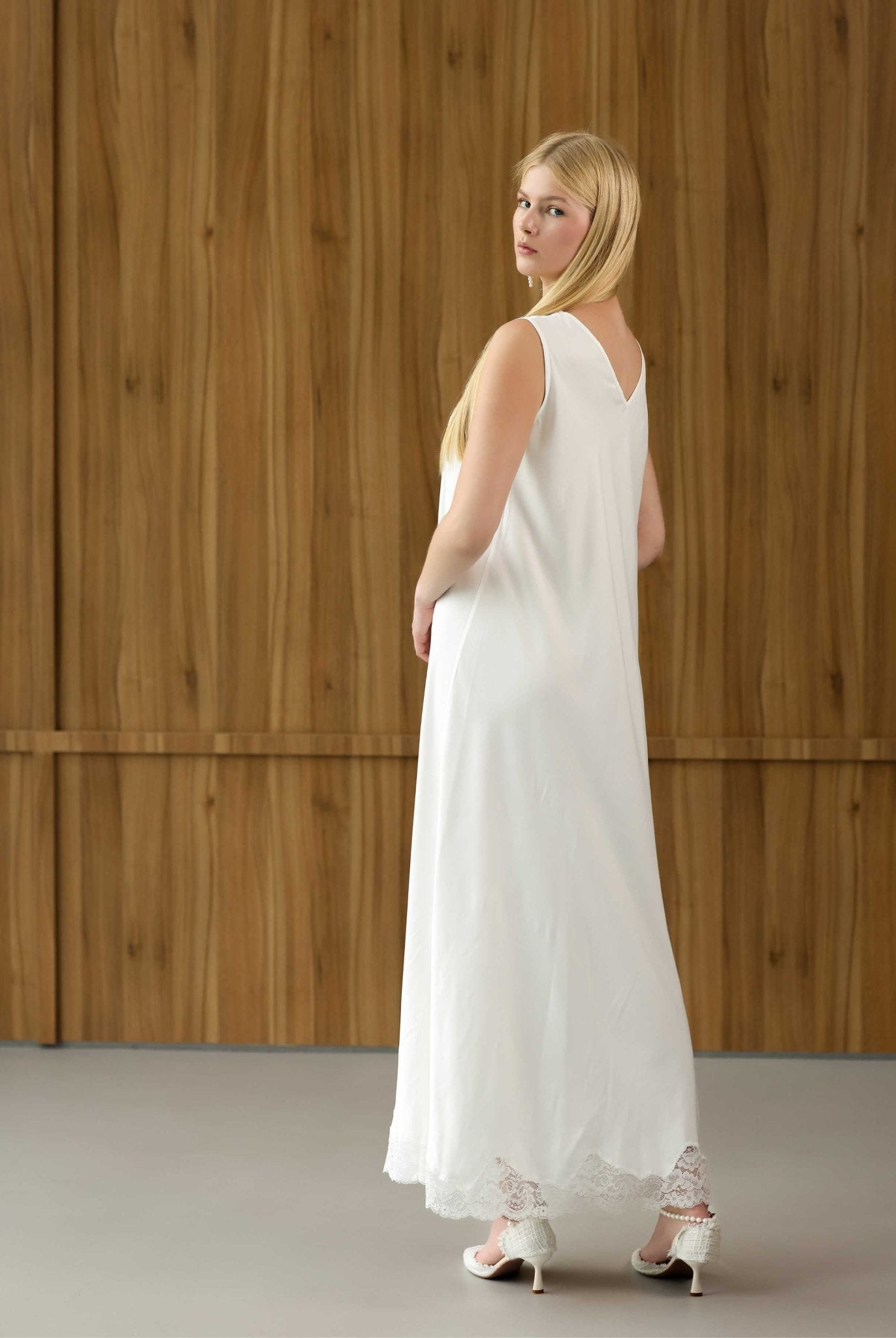 Side view of the white maternity nightgown, showcasing the open V-cut back and delicate lace-trimmed hem.