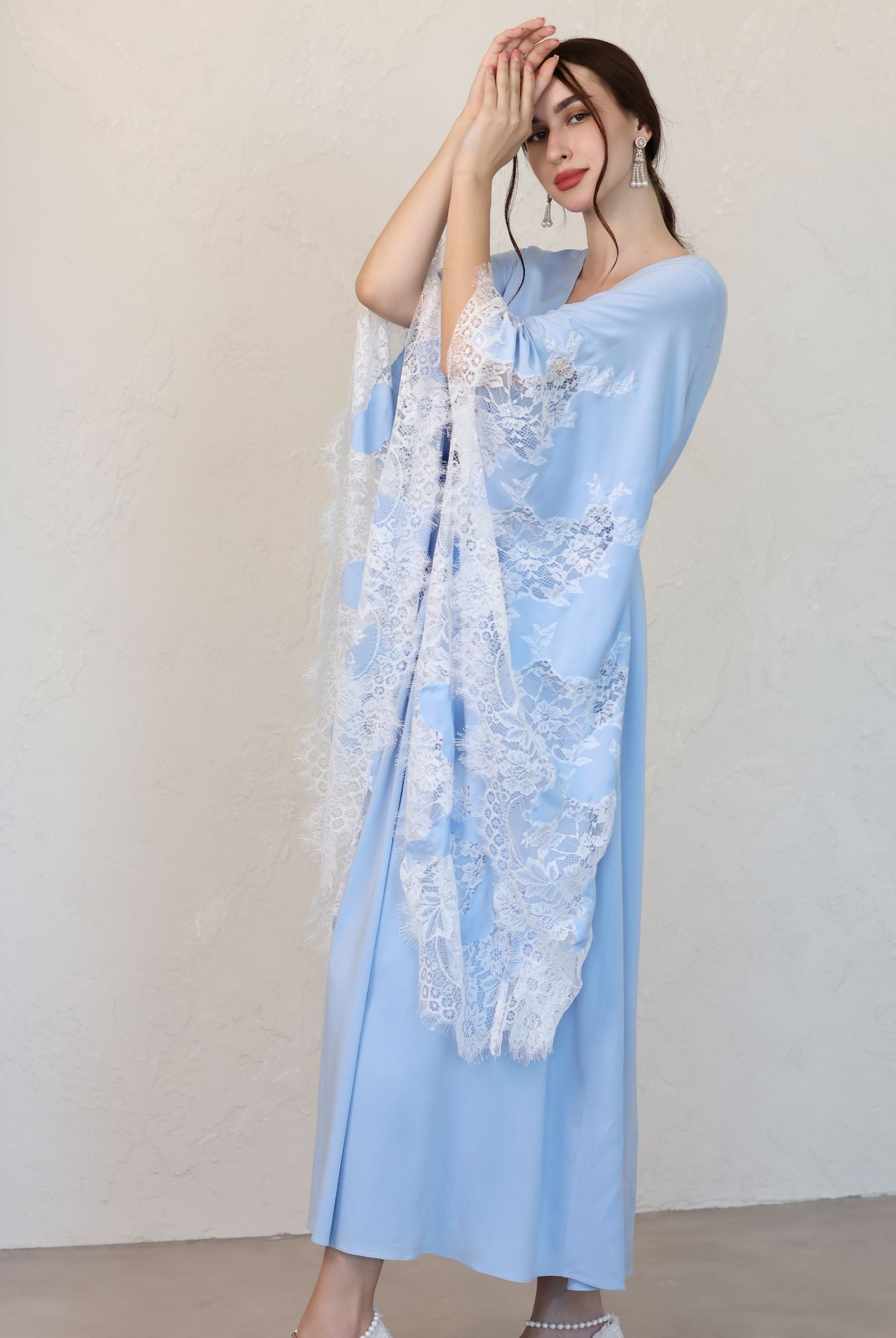 Side view in a soft cotton ensemble, emphasizing the flowing shape and the intricate lace detailing on the wide sleeves.