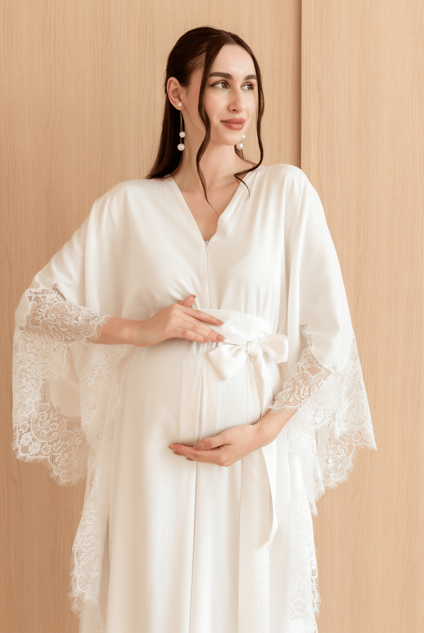 Mid-length shot of a woman holding her pregnancy bump, showcasing the intricate lace details and breathable fabric.