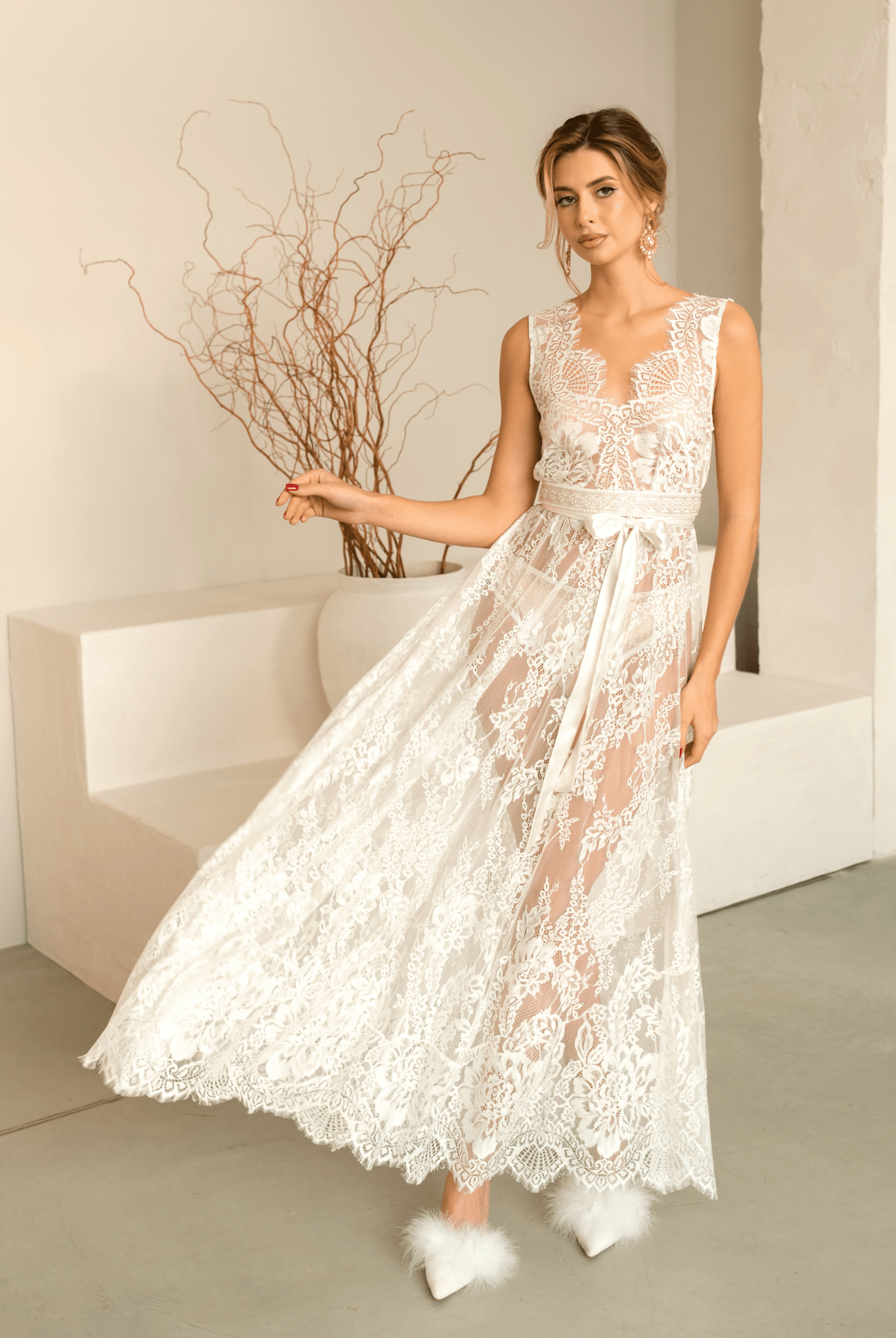 Elegant woman gracefully tossing the hem of her white Bridal Nightgown, showcasing the flowing lace fabric.