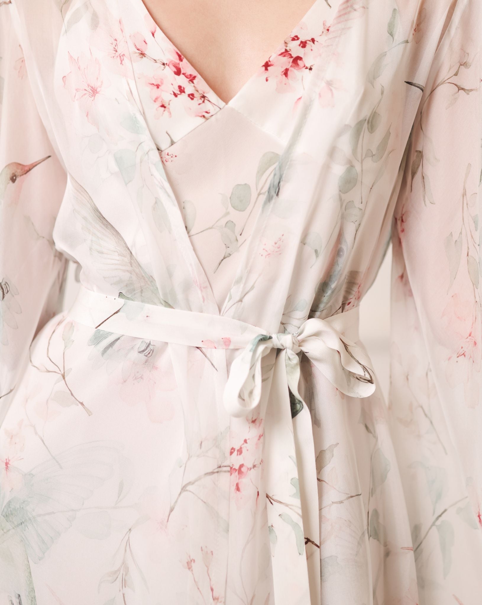 Close-up of a tied silk waist belt, focusing on the refined texture of the fabric and the floral design.