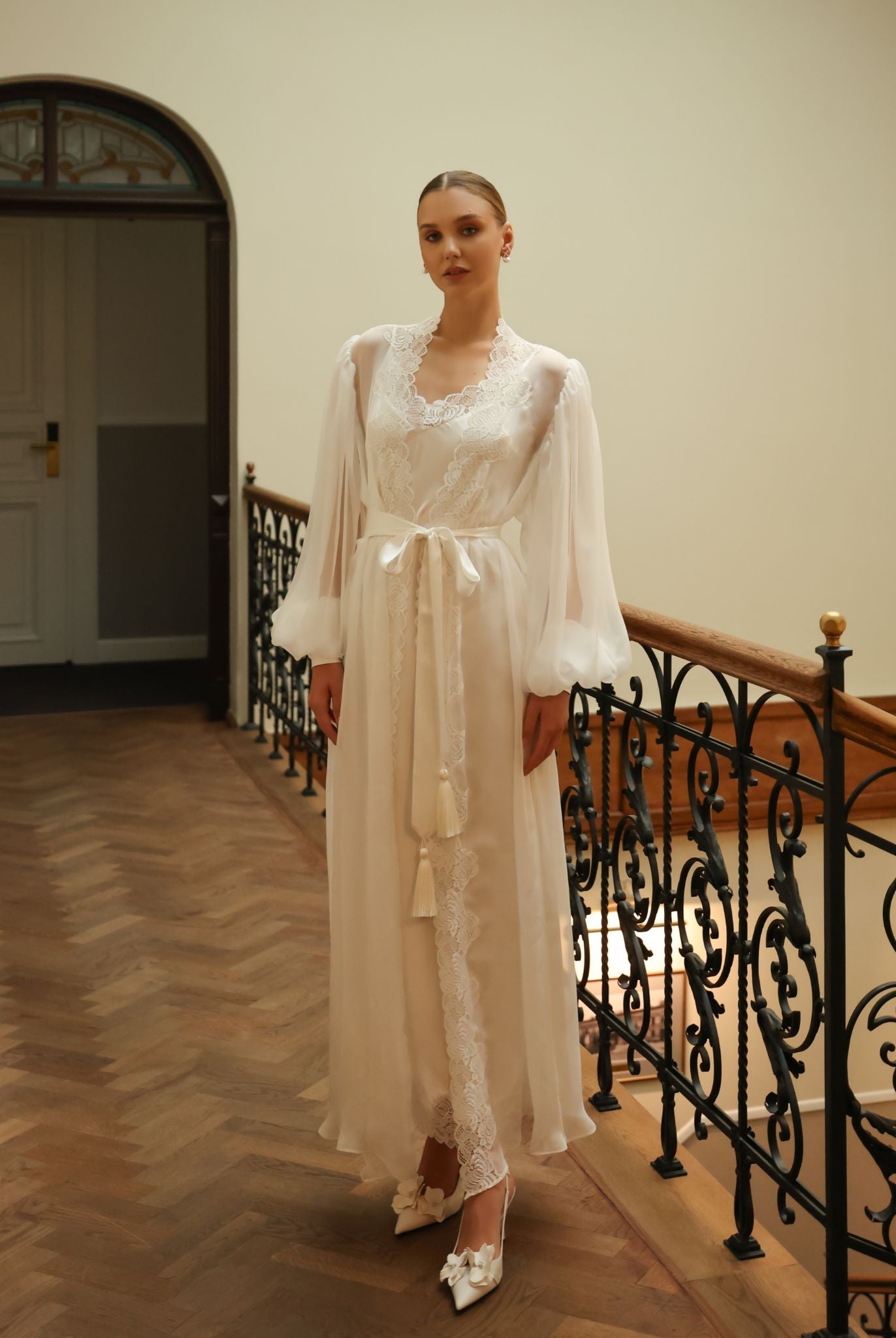 Standing by a staircase in a belted silk ensemble, illustrating the ultimate comfort and high-quality fabric.