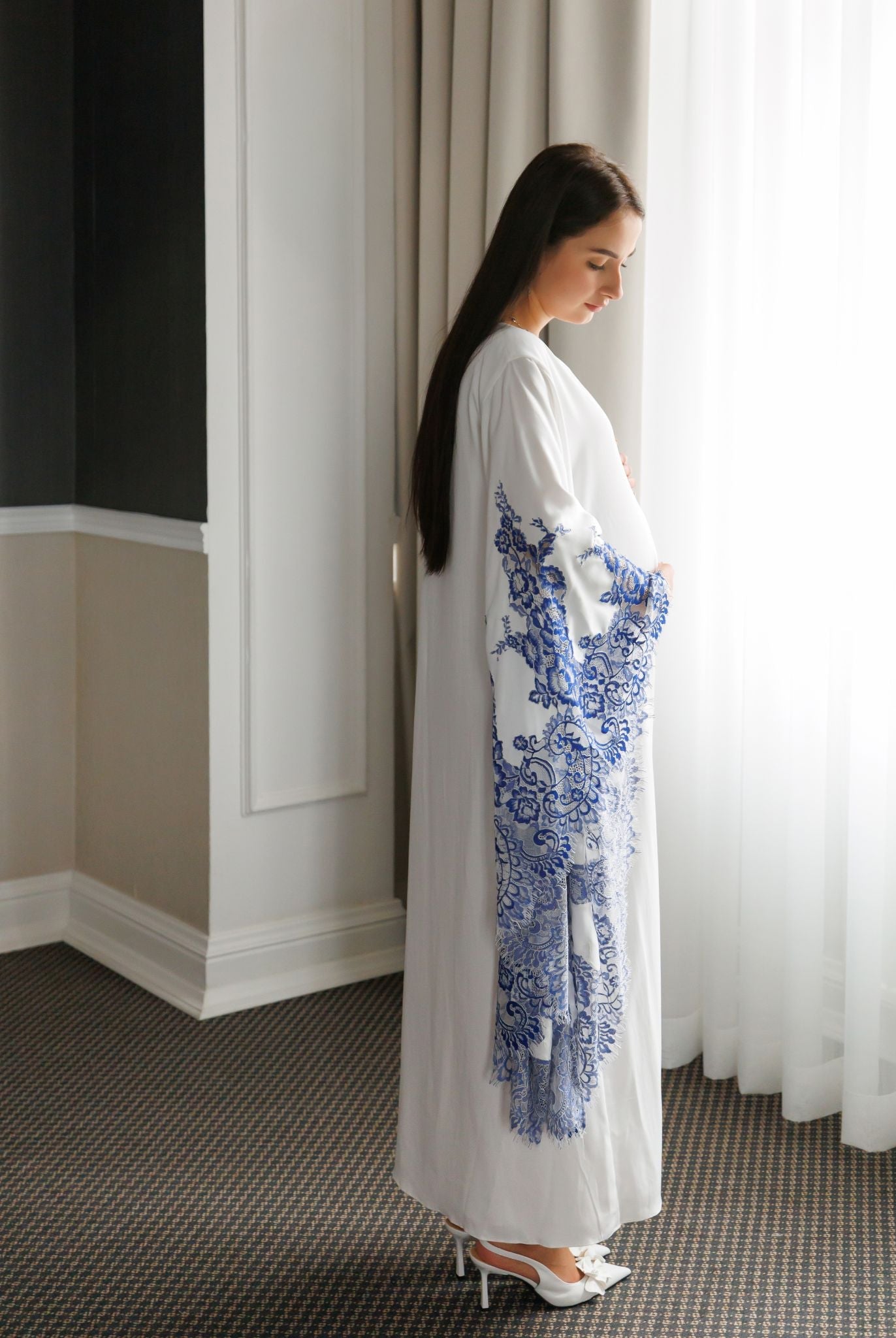 Side full-length pose focusing on the wide sleeves adorned with delicate and intricate lace embroidery.