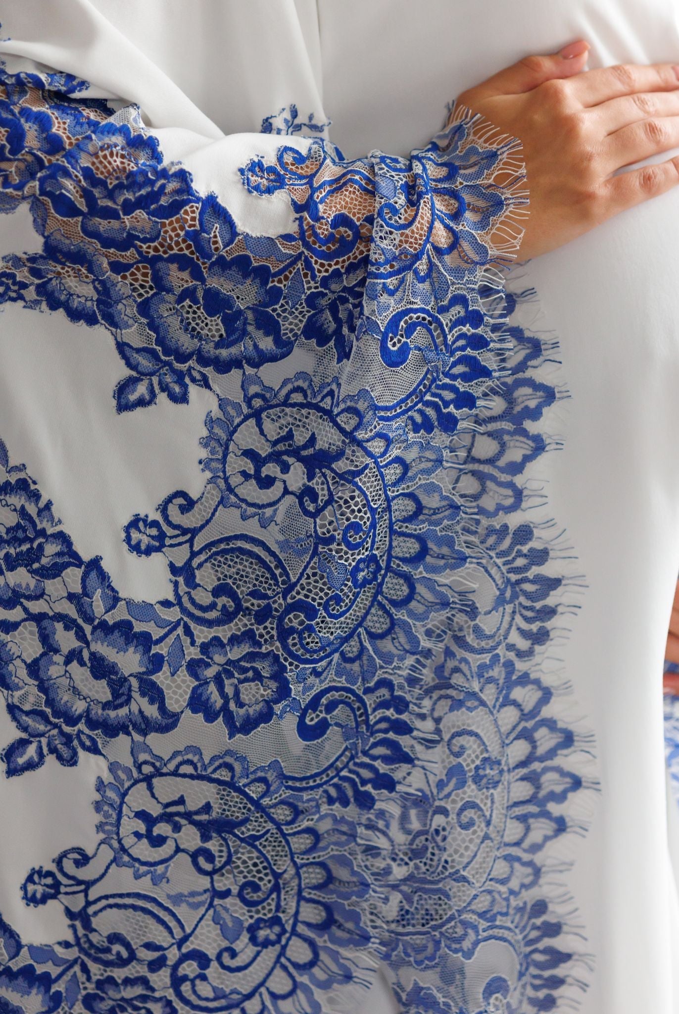 Close-up of hands on a pregnancy bump, showcasing the elegant lace details and high-quality craftsmanship of the sleeves.