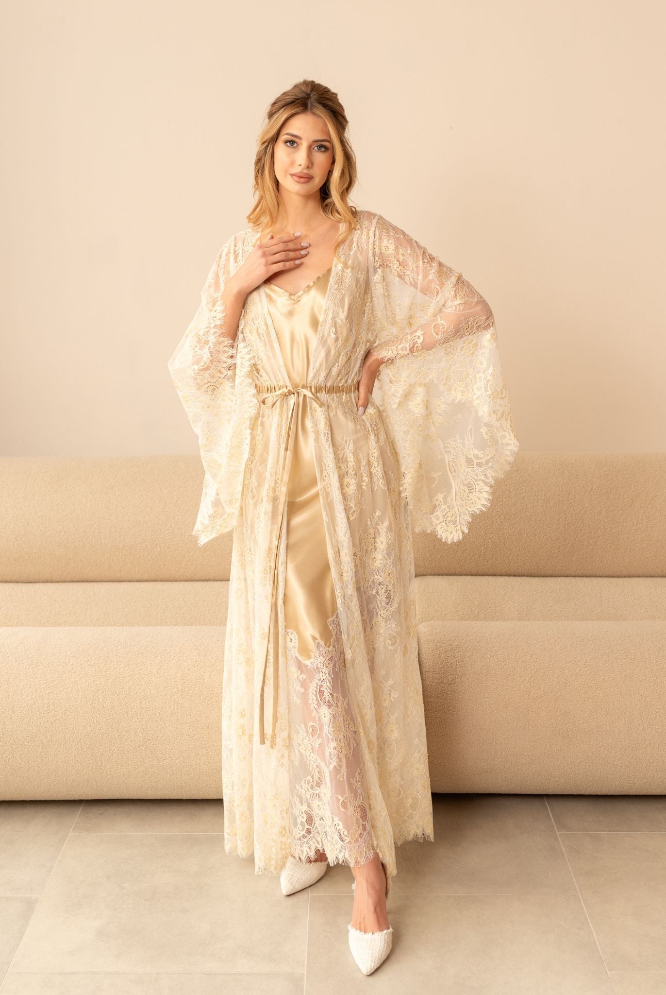 Model in champagne robe and gown with intricate embroidery, seated pose
