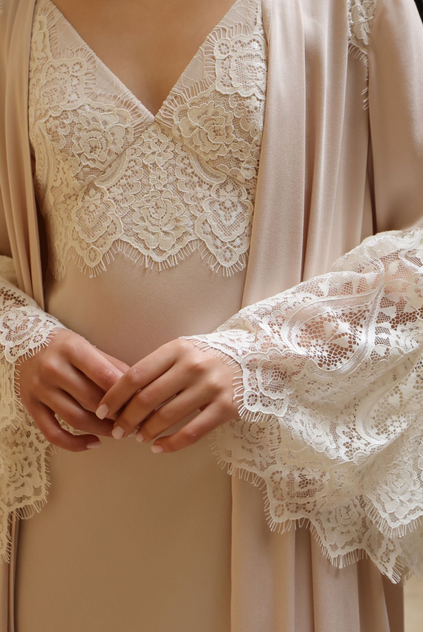 A close-up view from chest to hips, showcasing the delicate lace framing the neckline and the refined sleeve details.