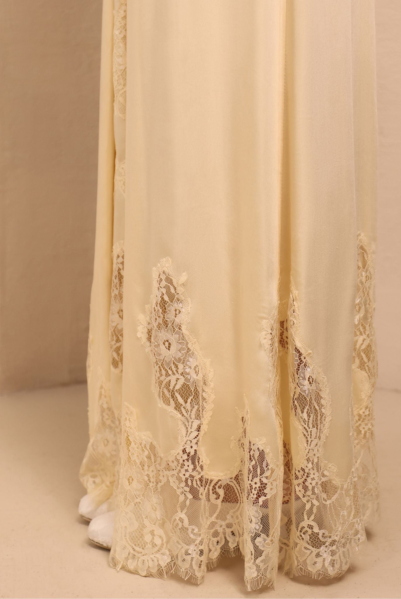 Close-up of the nightgown's hem, focusing on the soft lace patterns that add a layer of pure elegance to the design.