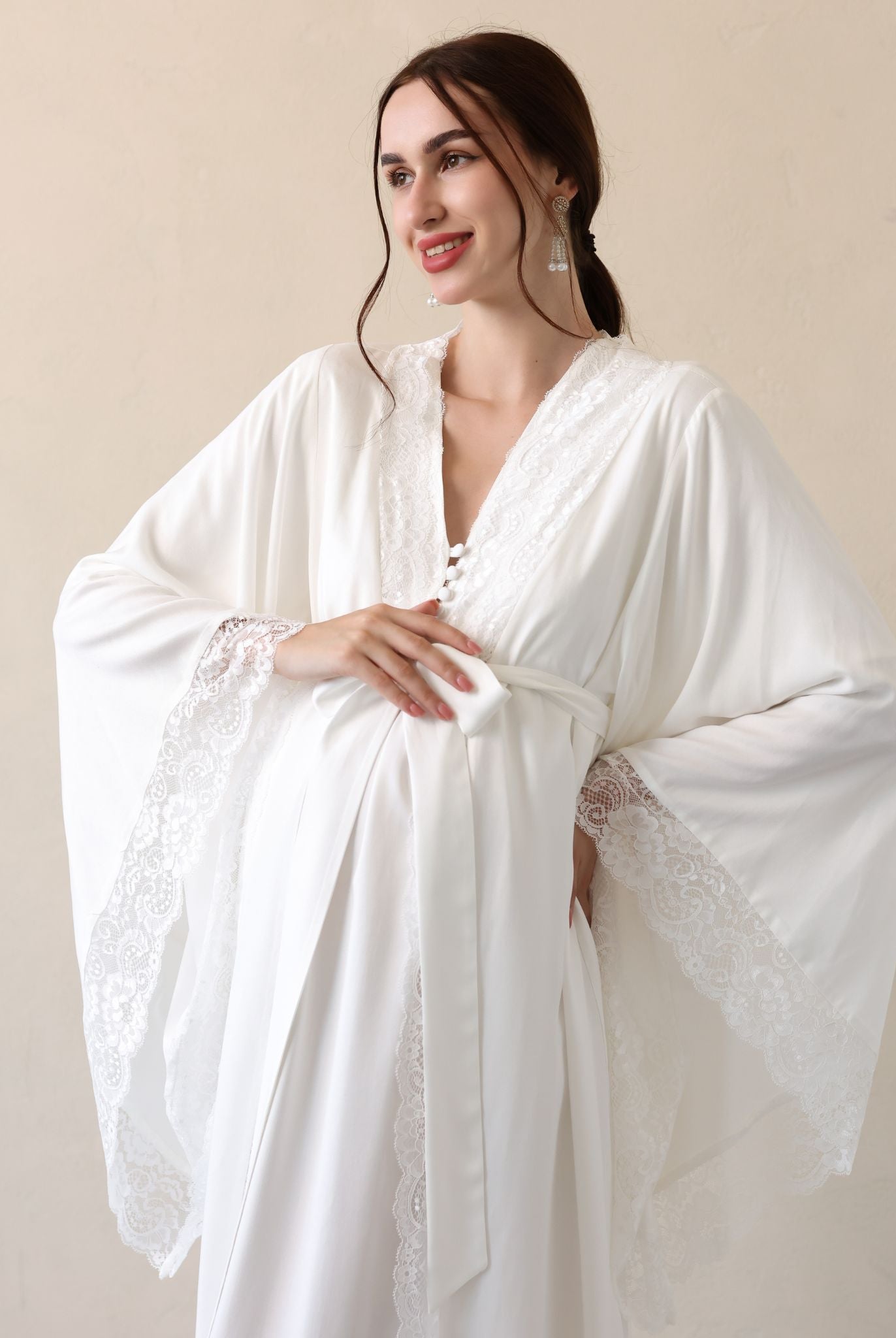 Posing with a hand on the belly to display the wide sleeves finished with fine lace for a sophisticated look.
