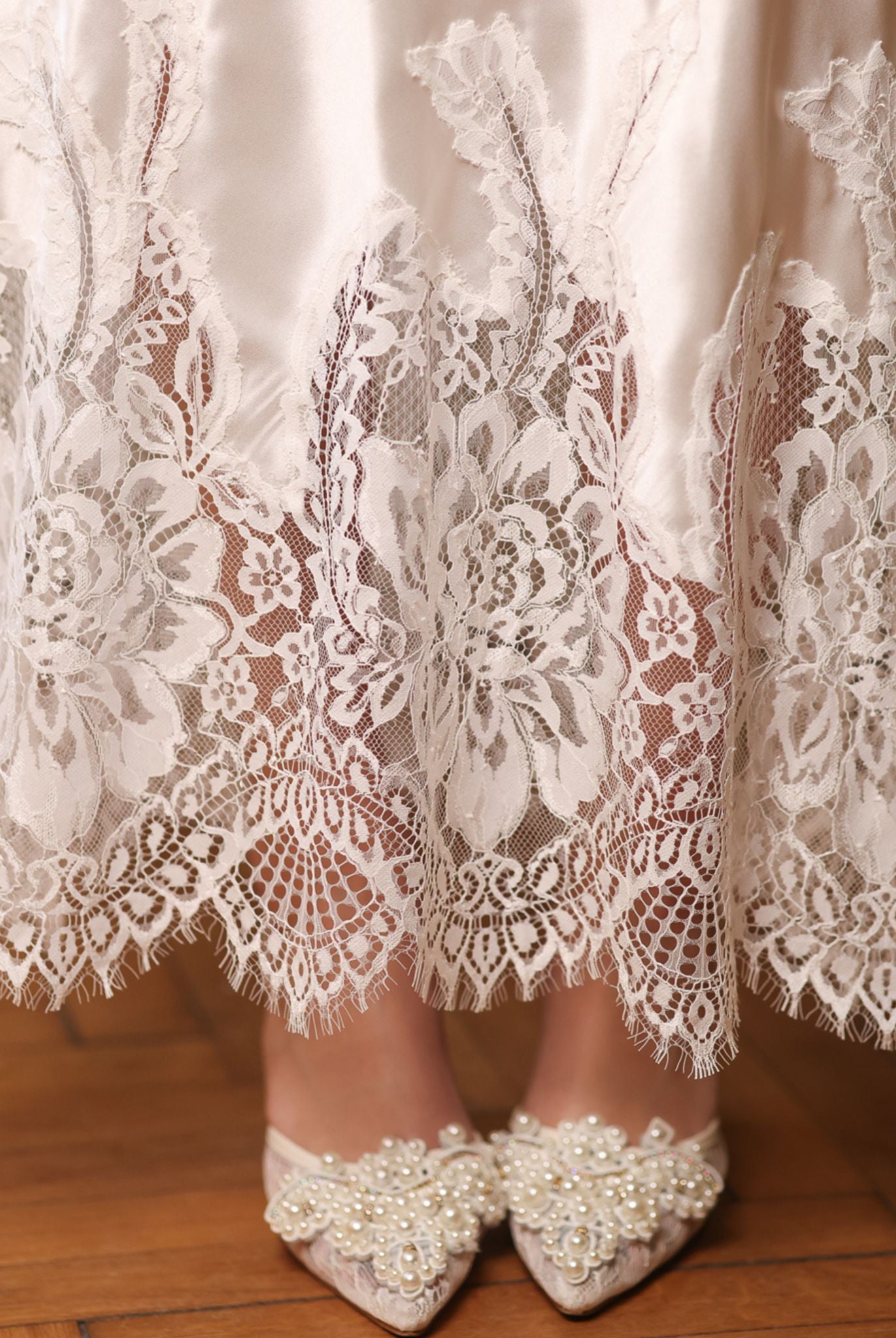 Close-up of the nightgown's hem, highlighting the delicate lace detailing and the gentle sheen of silk satin.