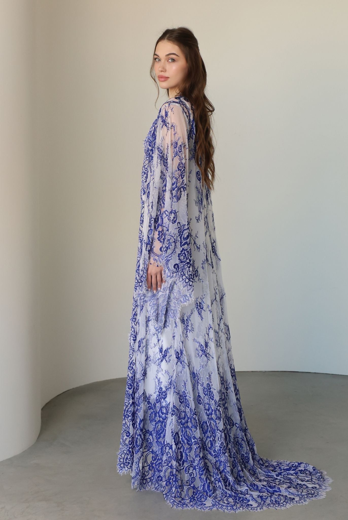 Side perspective of the attire, highlighting the graceful flow of the long lace train and the soft fabric.