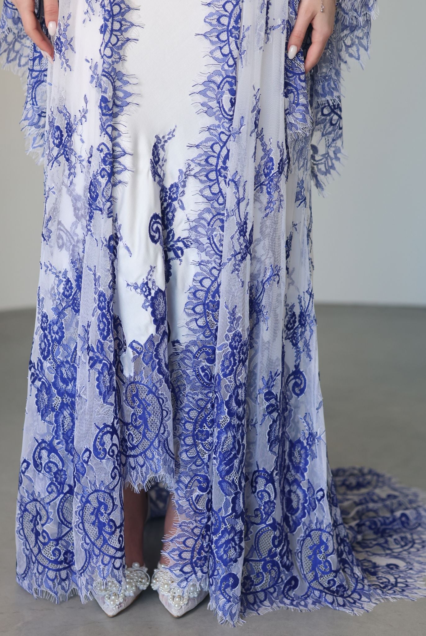 A detailed frontal view of the hem, focusing on how the intricate lace beautifully edges the gown and the robe.