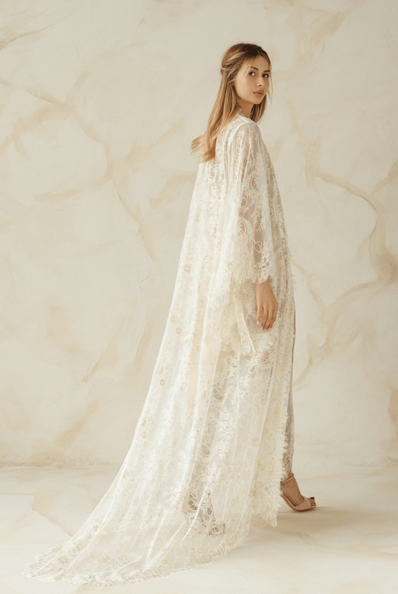 Full-length view of a woman wearing a sheer ivory lace robe over a satin nightgown