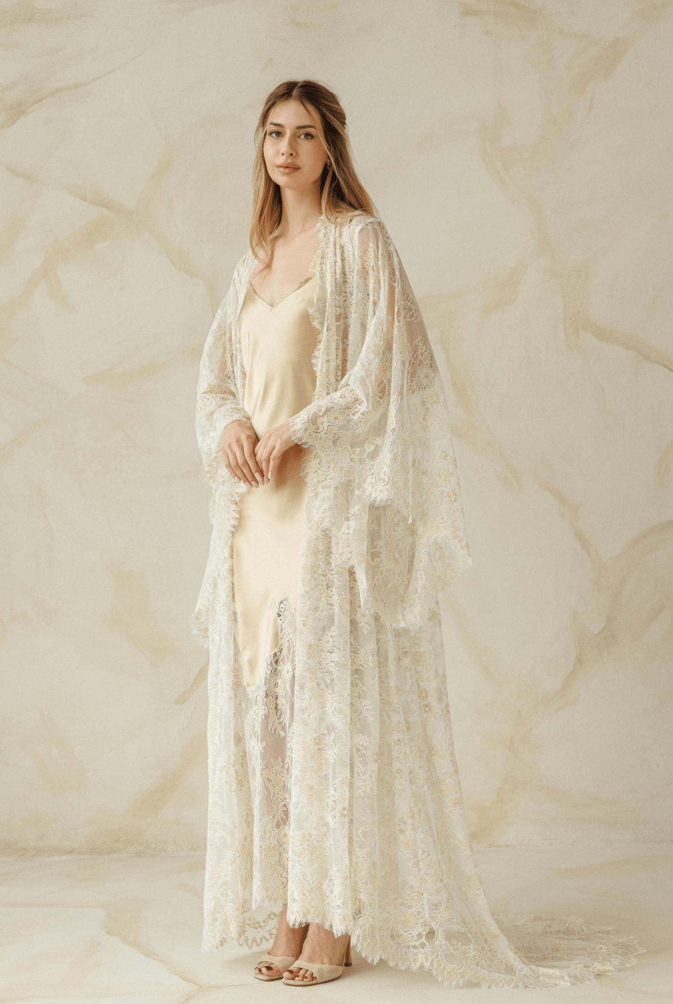 Woman layered in delicate robe over satin gown, hands resting on belly