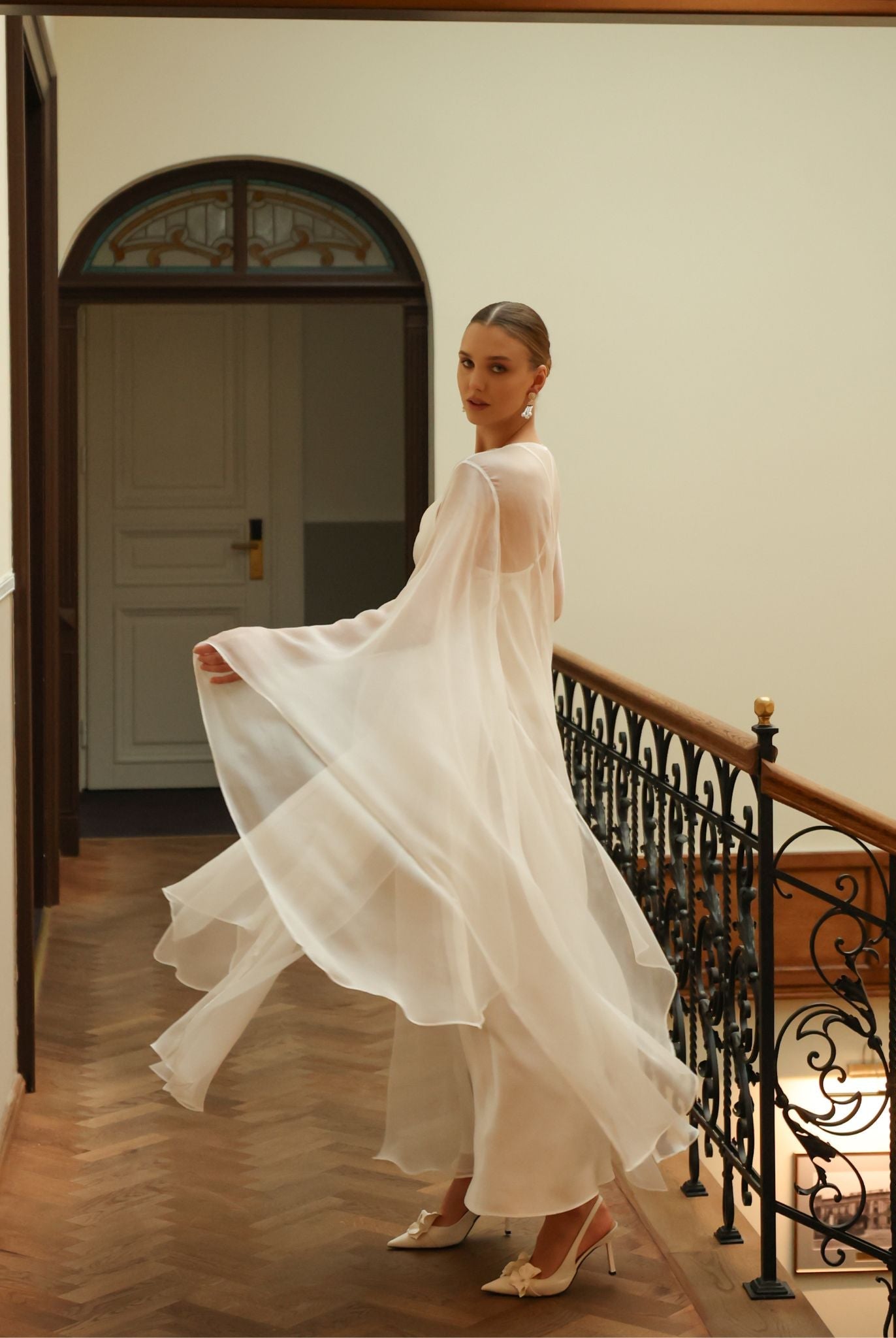 Dynamic shot of a sheer white silk robe in a swirl, emphasizing the weightless layer and romantic bridal design.