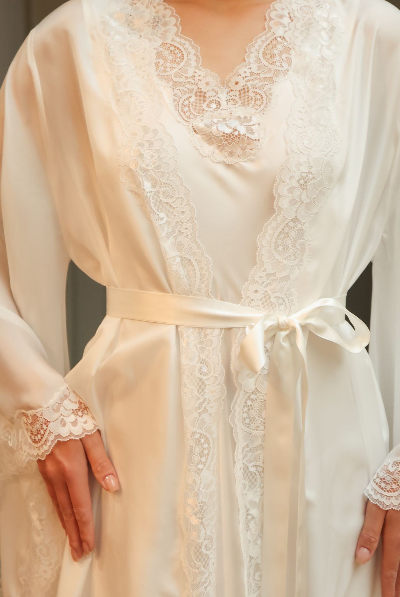 Detailed shot from neck to hips, focusing on the tied silk waist belt and the precise stitching of the wrap-over style.