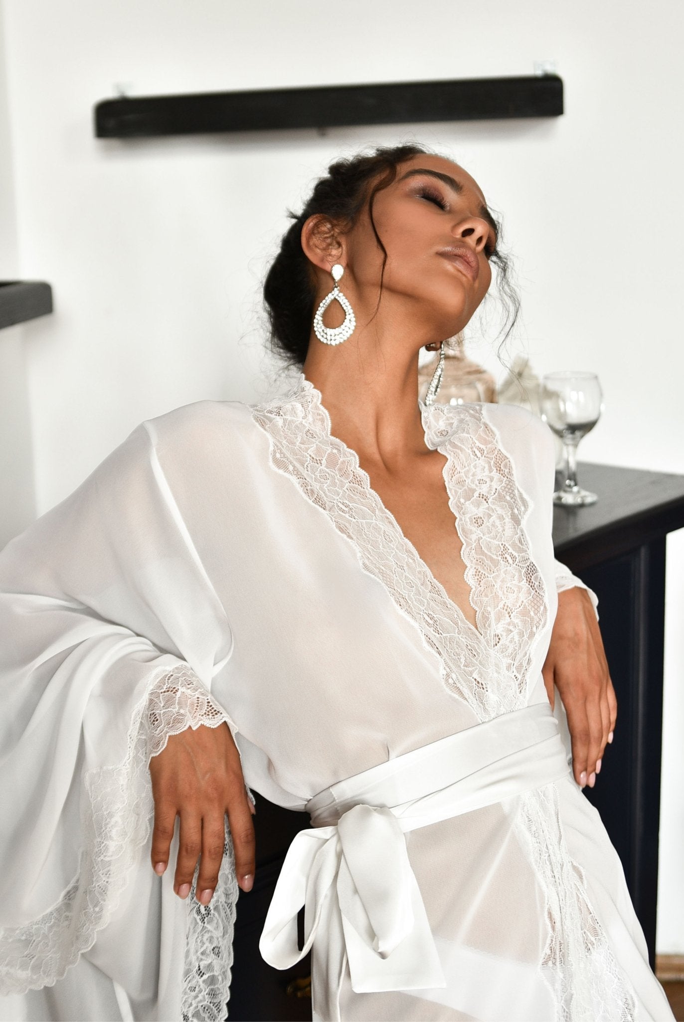 Woman in white bridal robe seated beside a piano