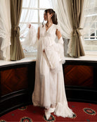 A creative shot of an expecting woman by the window, with the robe draped gently over the shoulders.
