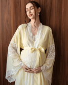 Tender maternity shot in a yellow cotton robe with a sash tied over the baby bump, highlighting soft lace details.