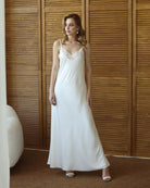 Bride in flowing white robe and nightgown, standing near wood panel