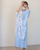 Side view in a soft cotton ensemble, emphasizing the flowing shape and the intricate lace detailing on the wide sleeves.