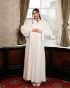 Frontal shot of an expecting woman with hands on the waist, highlighting the delicate ruffle framing the waistline.