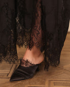 Close-up of the slipper on one foot, highlighting the delicate French lace adornment and meticulous craftsmanship.