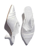 A shot of the slippers on a white background, where one shoe stands and the other lies to show the heel.