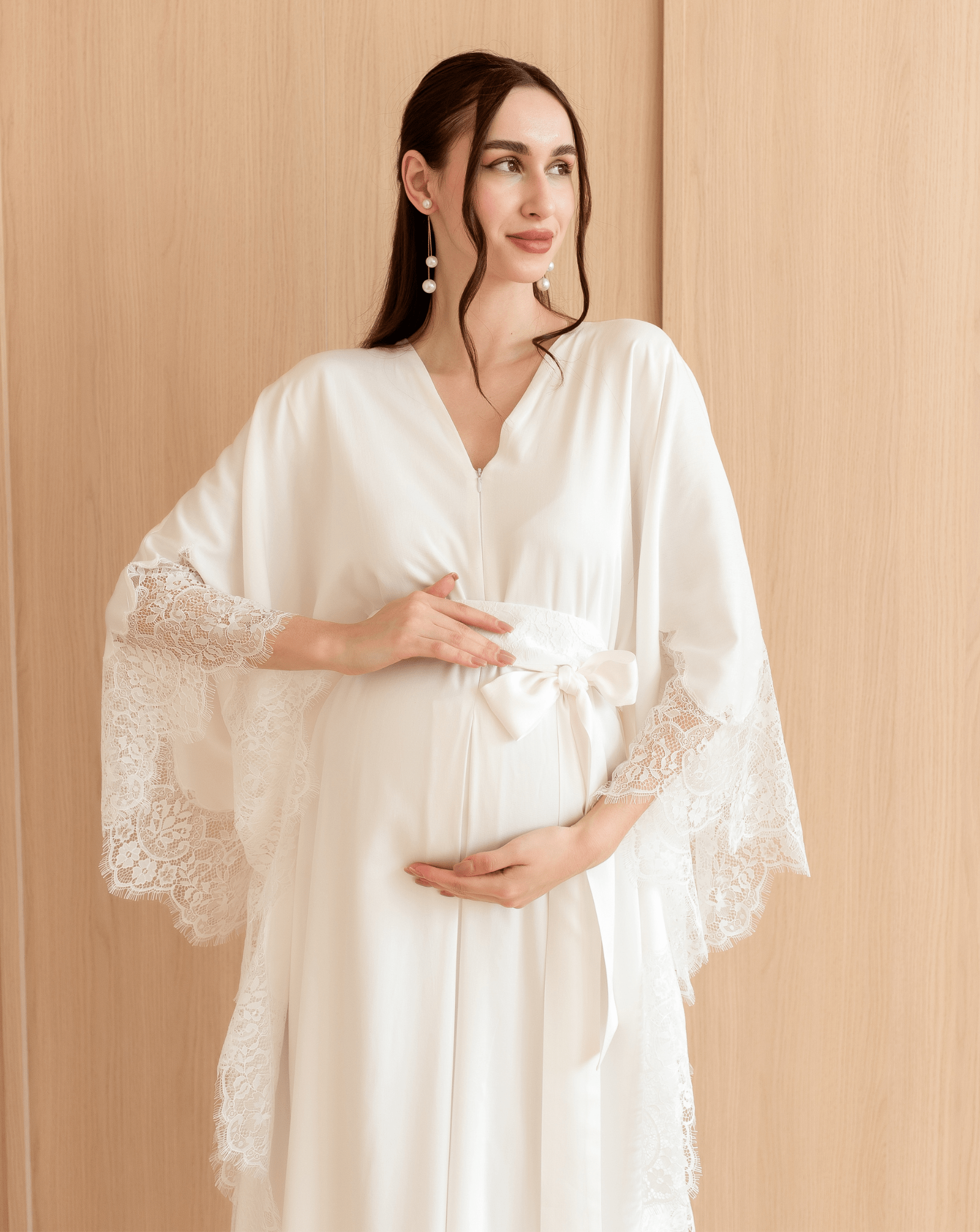 Mid-length shot of a woman holding her pregnancy bump, showcasing the intricate lace details and breathable fabric.