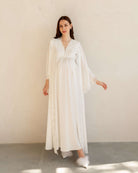 Full-length view of a white maternity robe with a belt tied over the baby bump, featuring wide lace-trimmed sleeves.