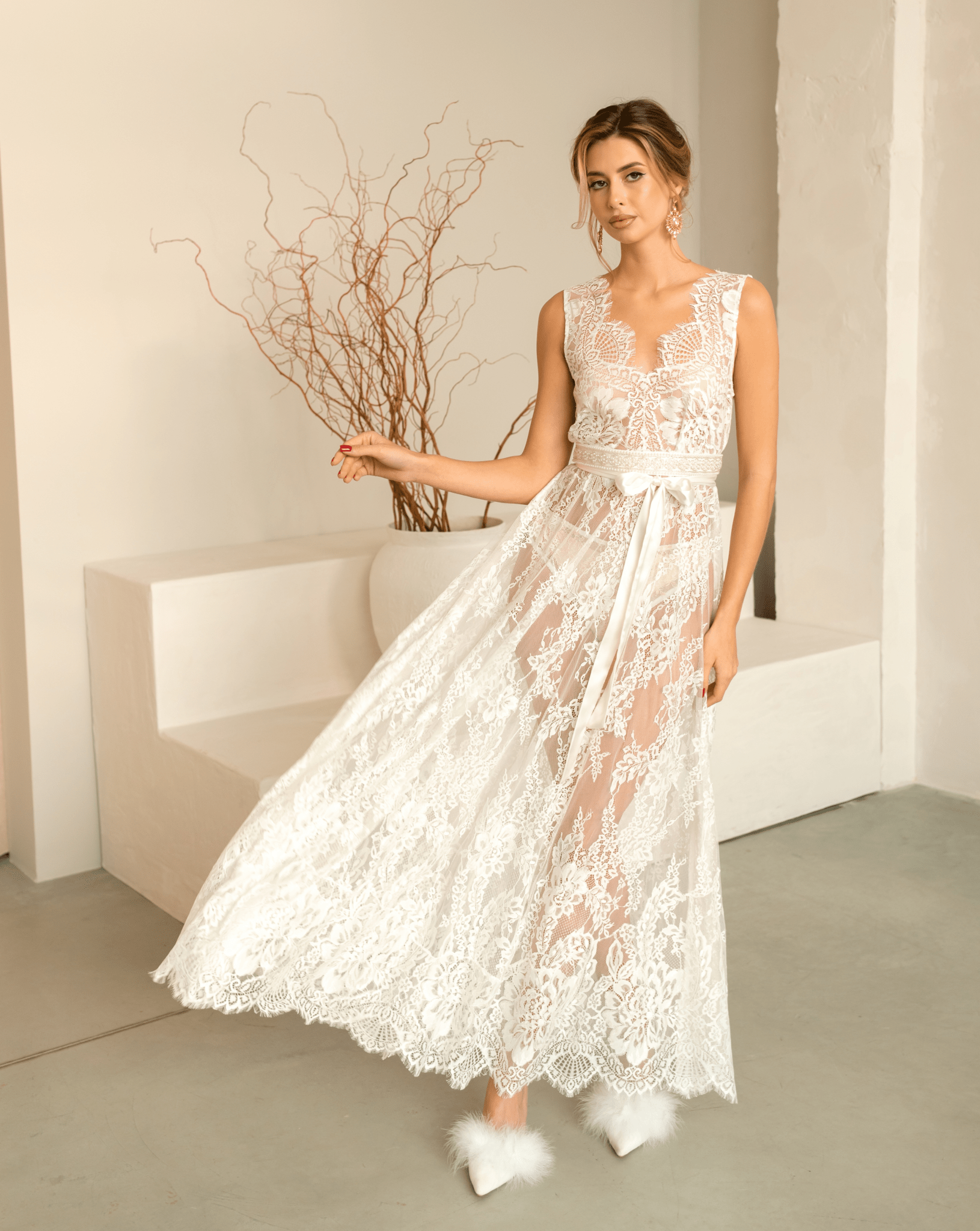 Elegant woman gracefully tossing the hem of her white Bridal Nightgown, showcasing the flowing lace fabric.