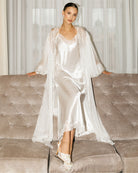 Full-length view of the white silk ensemble while seated, showcasing the flowing chiffon and elegant floor-length hem.
