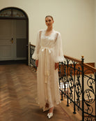 Standing by a staircase in a belted silk ensemble, illustrating the ultimate comfort and high-quality fabric.