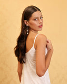 Waist-up view of a minimalist white nightdress, showcasing the smooth fabric and delicate shoulder straps.