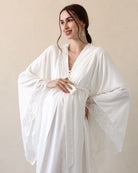 Posing with a hand on the belly to display the wide sleeves finished with fine lace for a sophisticated look.