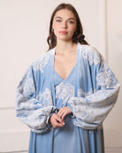 Shot from head to waist capturing the poetic movement of airy balloon sleeves with lace-trimmed wrists.