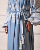 Close-up of a velvet tie at the waist, illustrating the elegant wrap-over style and rich texture of the garment.