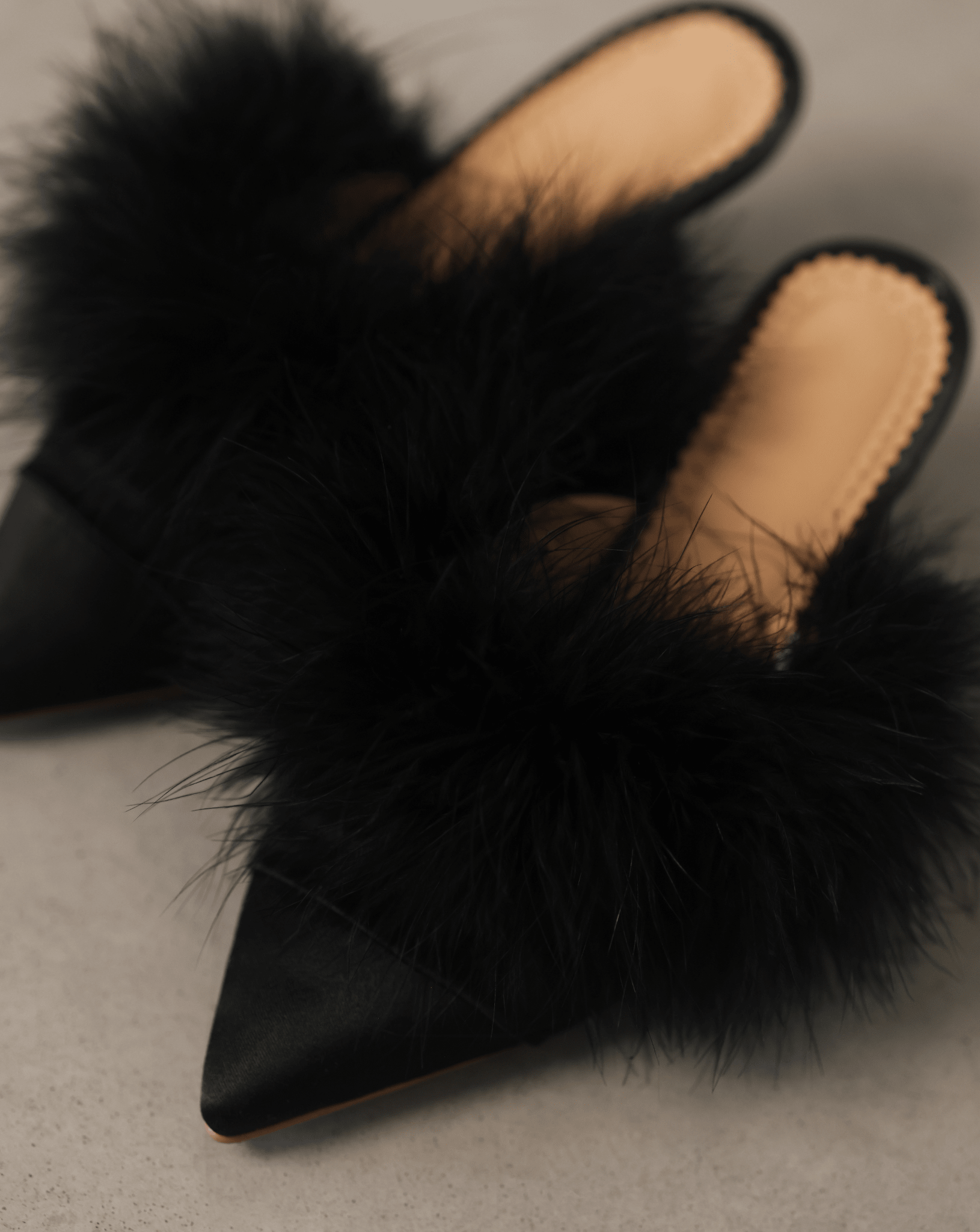 A close-up top view of the Satin Slippers on the ground, focusing on the satin base and feather adornment.