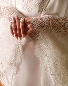 Detailed shot of the hands, focusing on the luxurious lace trimming the wide sleeves of the silk habotai robe.