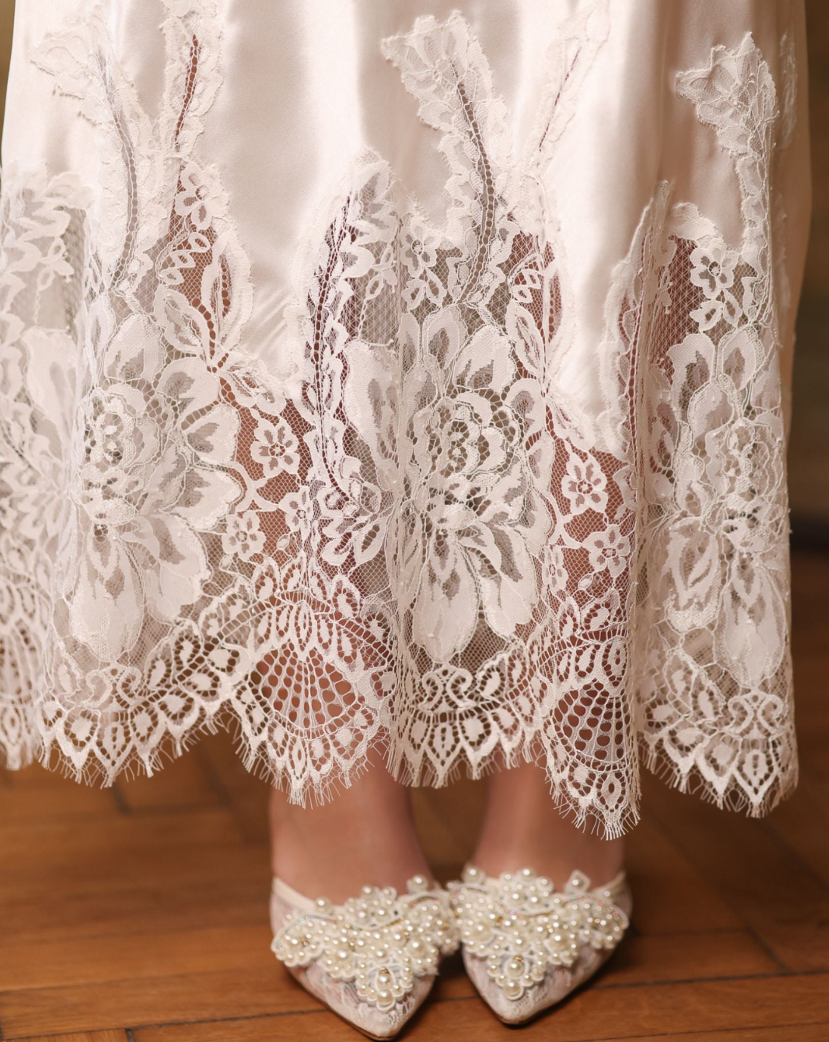 Close-up of the nightgown's hem, highlighting the delicate lace detailing and the gentle sheen of silk satin.