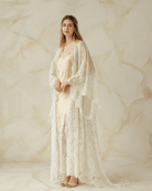 Woman layered in delicate robe over satin gown, hands resting on belly