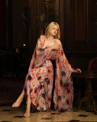 Creative shot sitting in a floral silk ensemble, highlighting the luminous sheen and artistic atmosphere of the look.