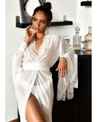 Woman in sheer chiffon robe smiling while standing near a mirror